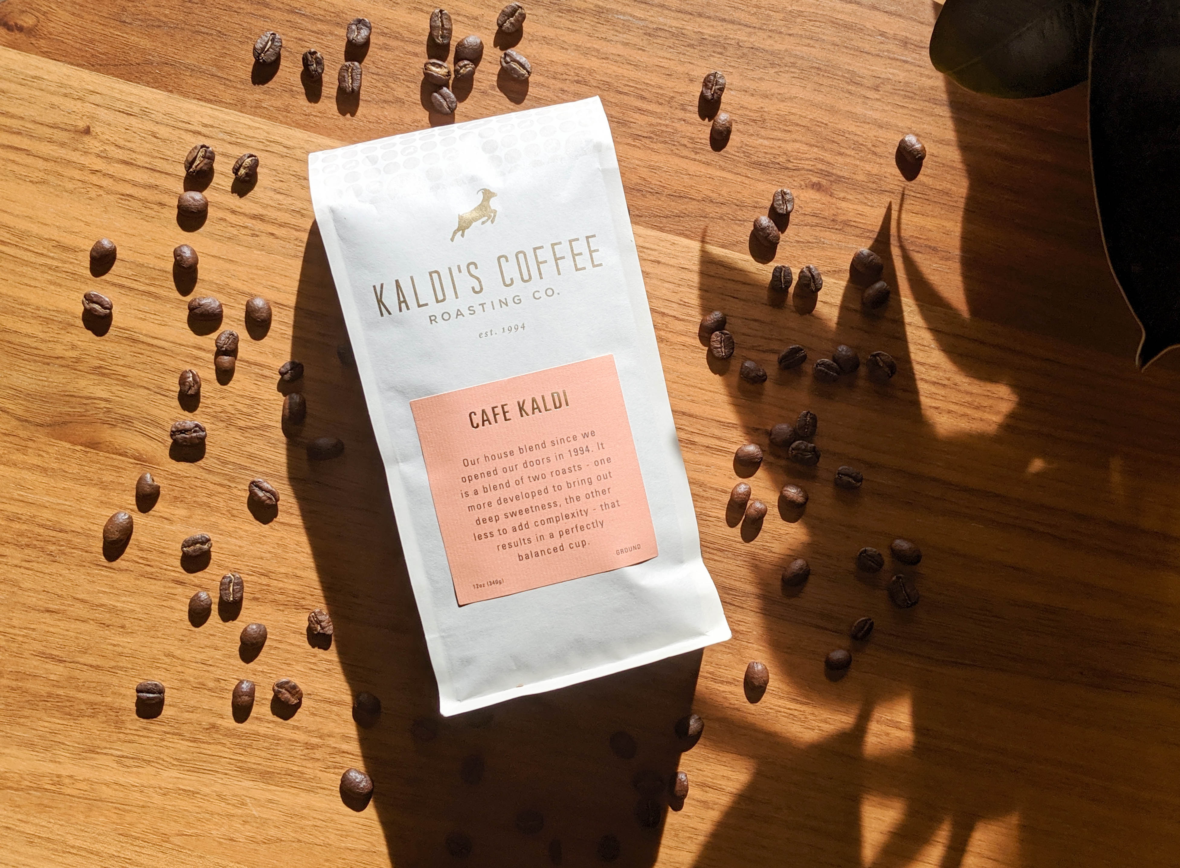 A Kaldi's Coffee 12oz bag on a table with coffee beans scattered