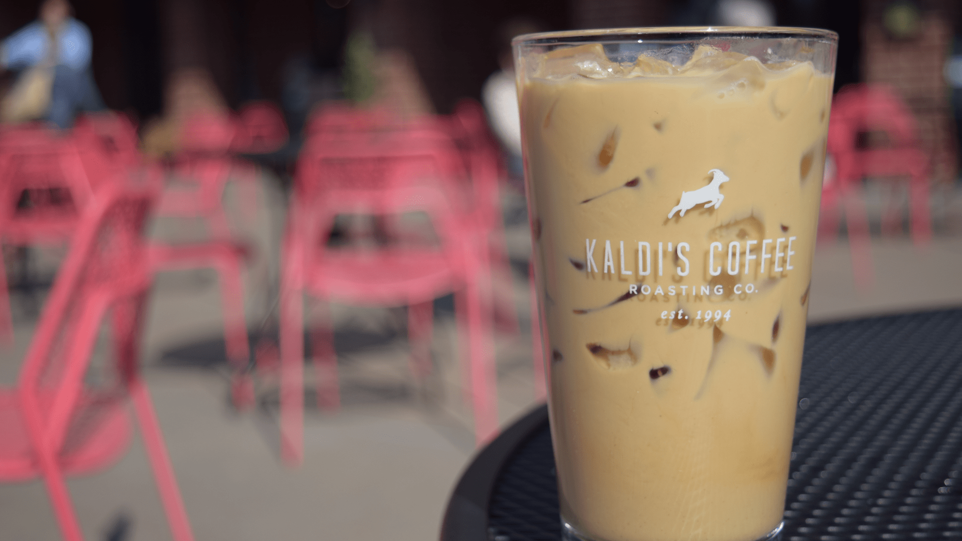A glass filled with an iced latte sitting on a patio table