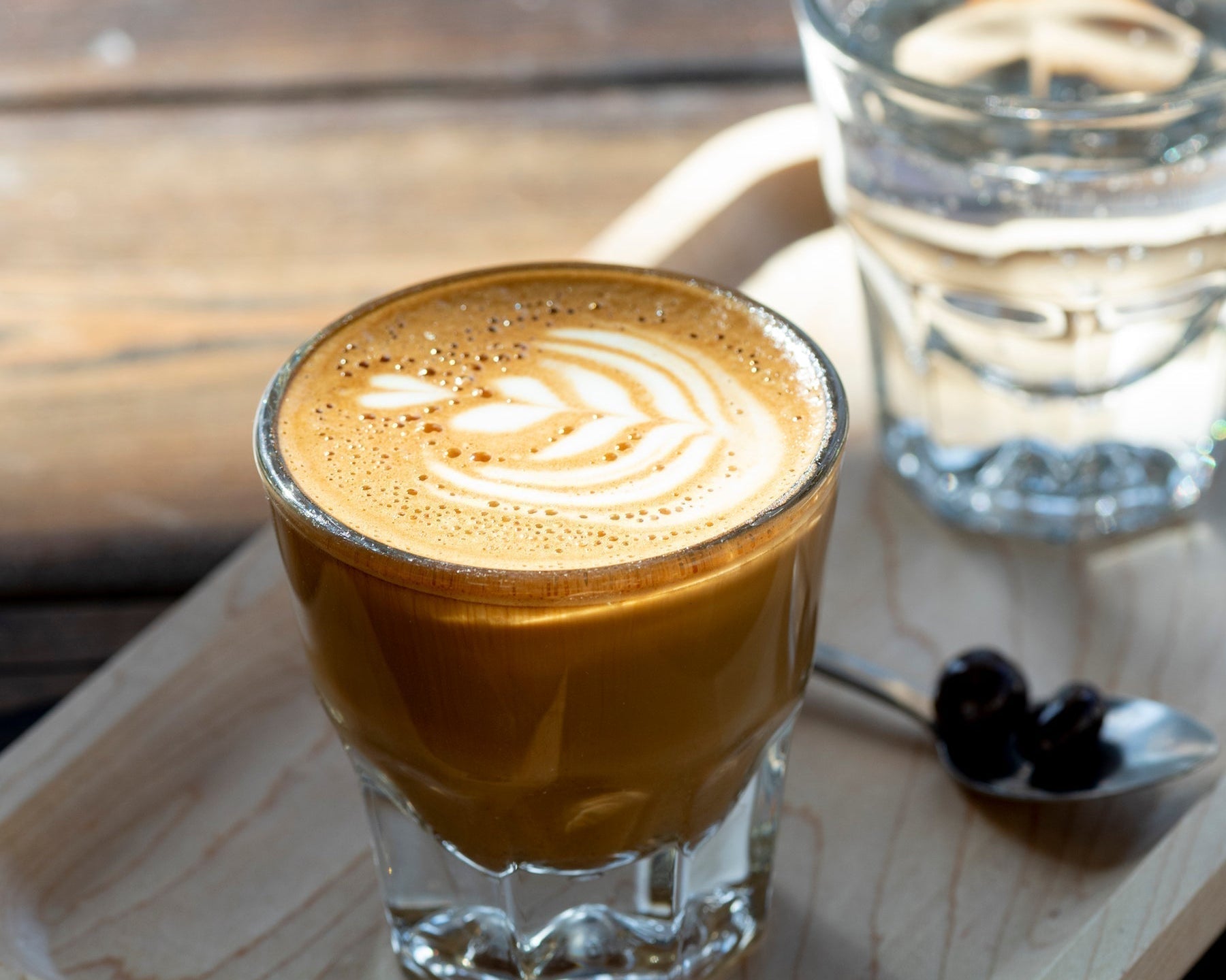 A Gibraltar sitting on a wooden board - The Gibraltar is an espresso drink with 2 shots and a little bit of foamed milk