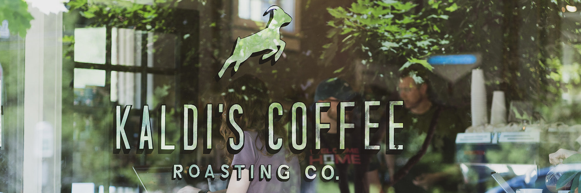 The front window pane of Demun Cafe, Kaldi's Coffee Roasting Co. text visible