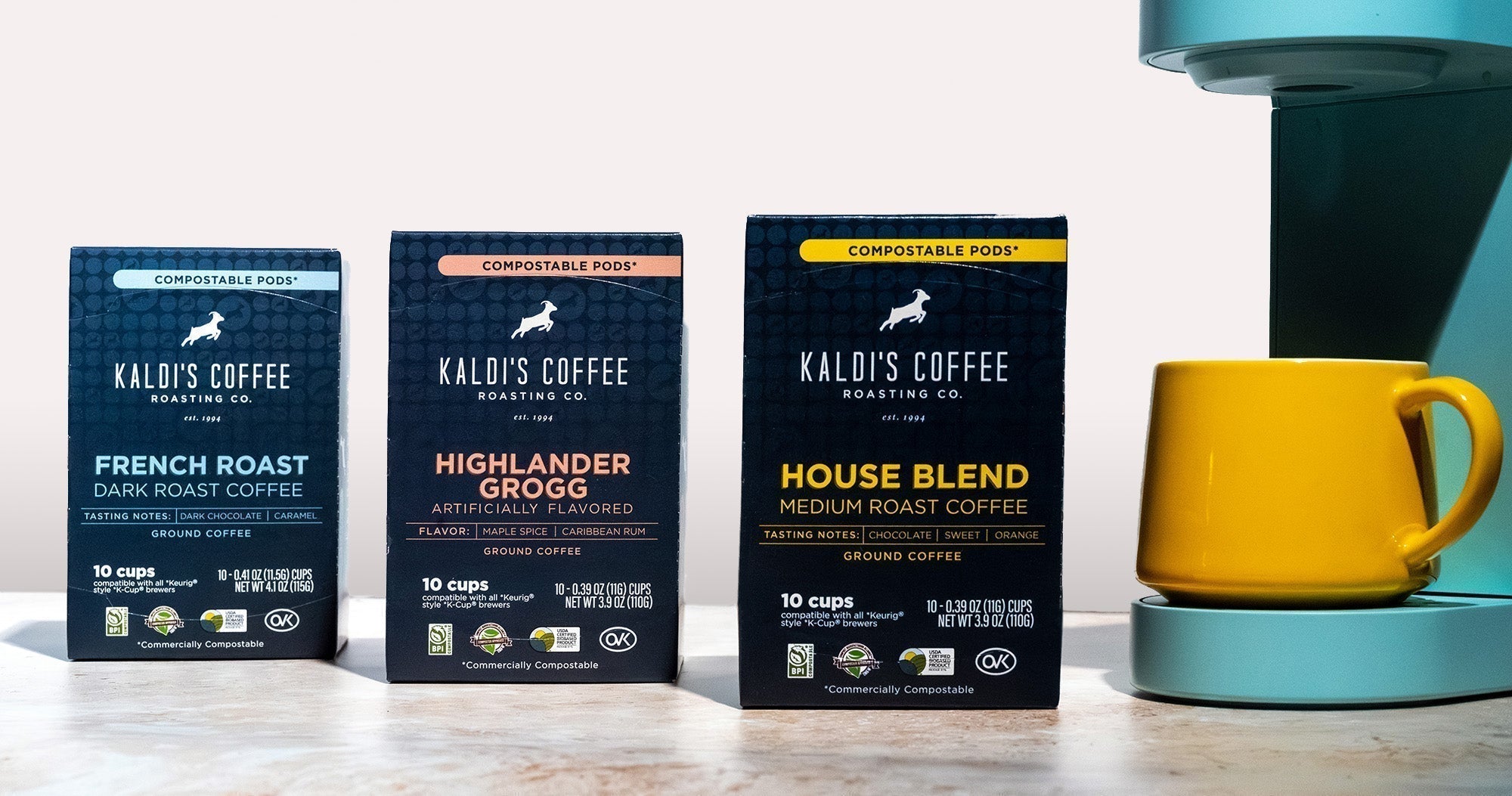 3 boxes of coffee pods next to a pod coffee maker