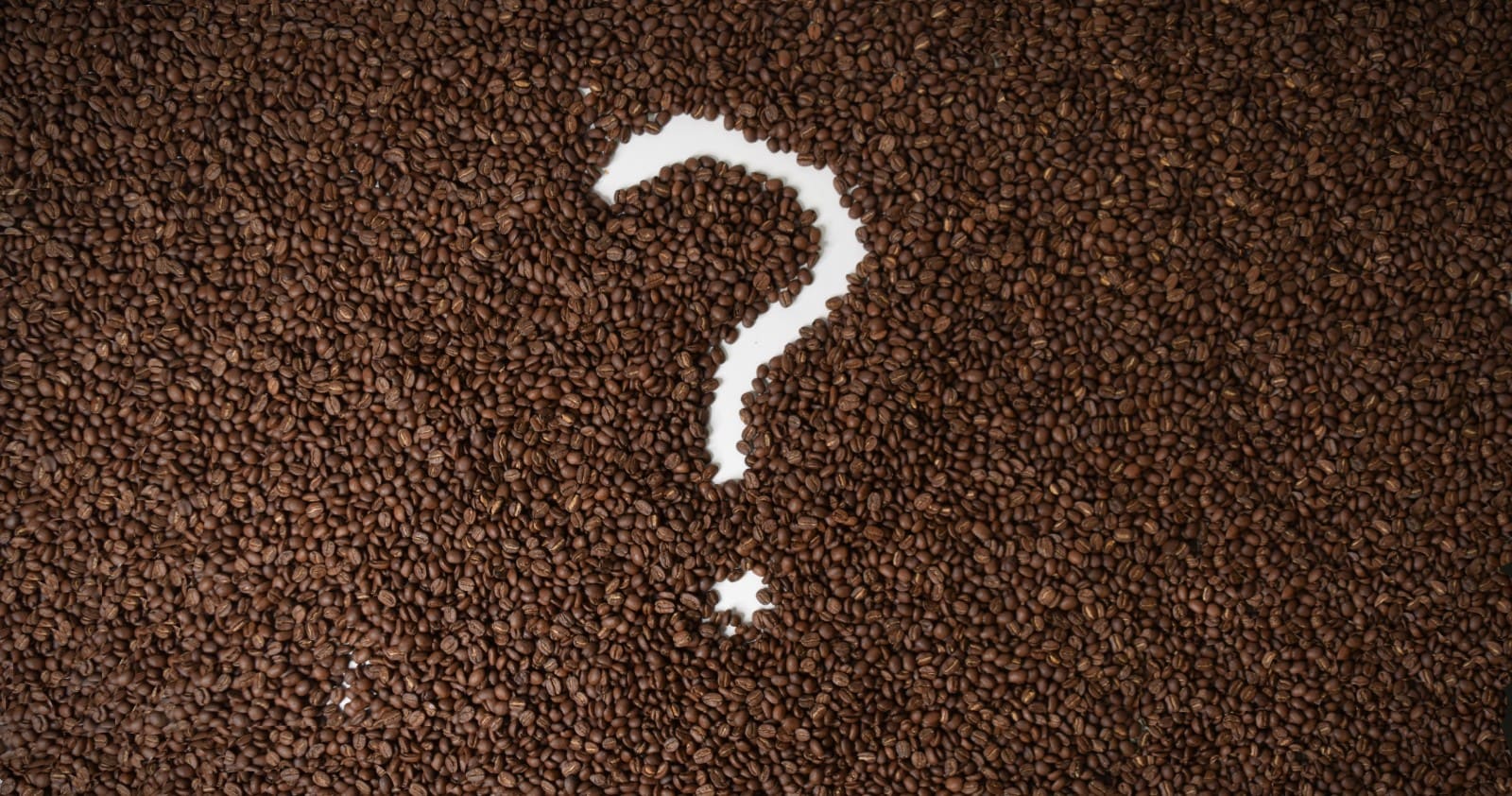 A Question mark carved into a bed of coffee beans