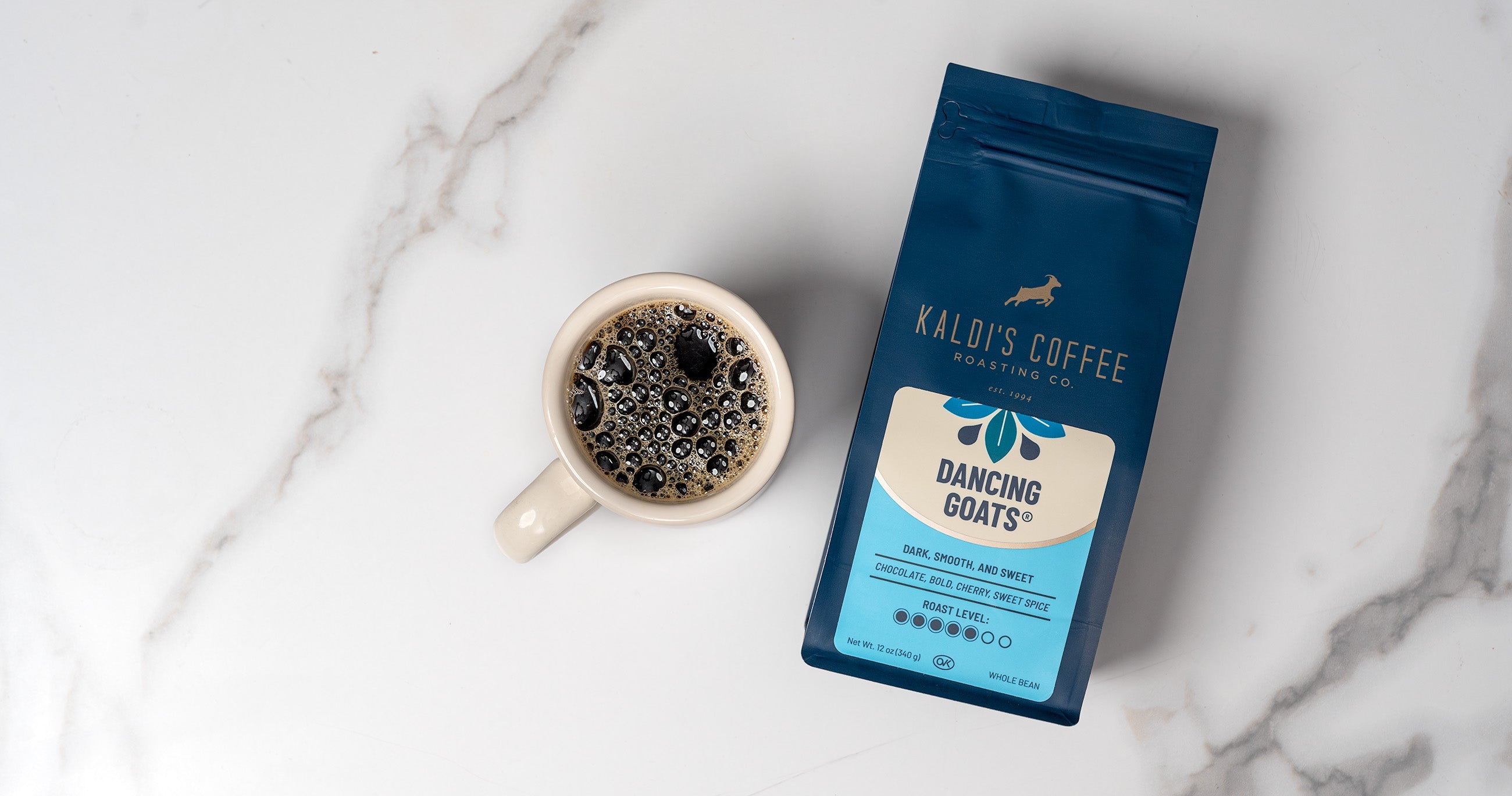 12 ounce bag of Dancing Goats blend next to a mug of coffee