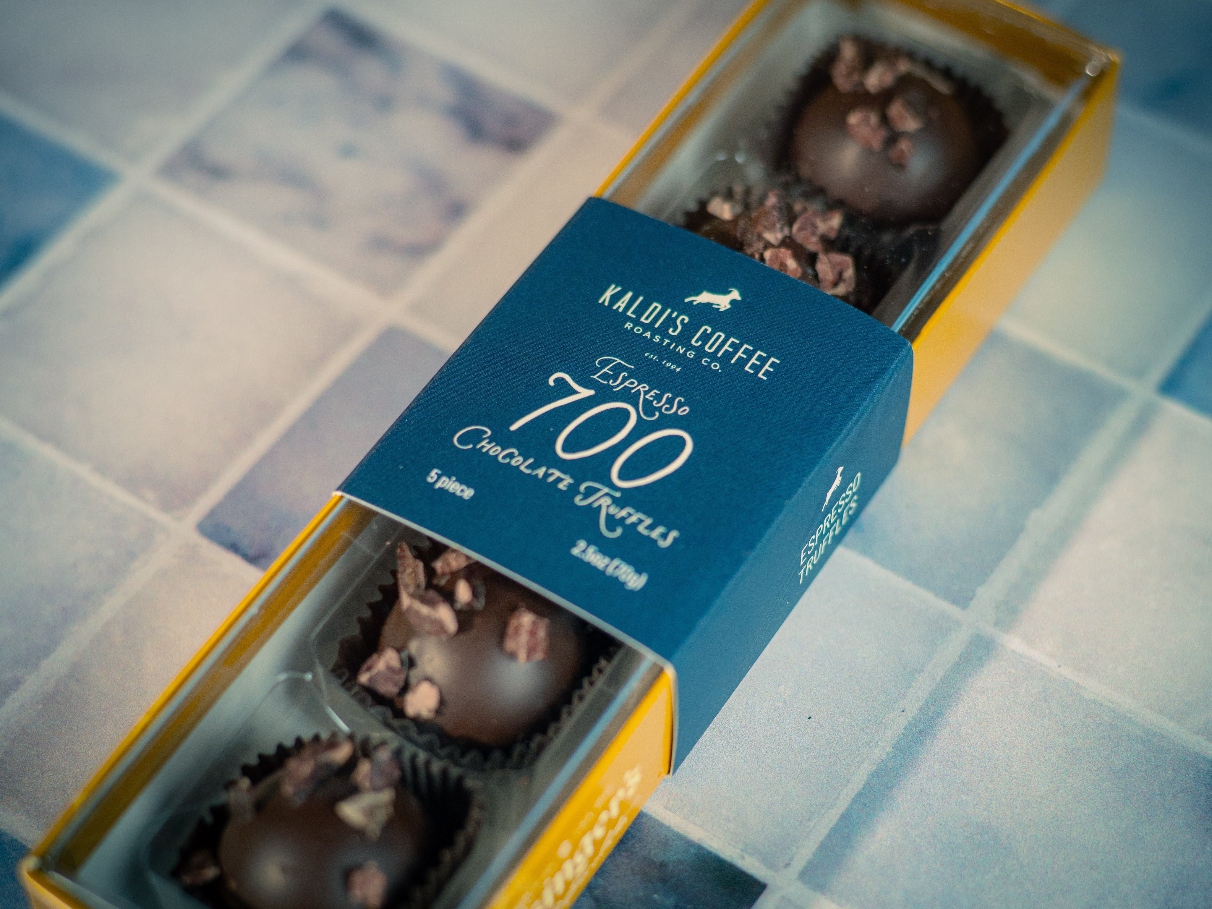 Box of chocolates with a blue label on a tiled floor