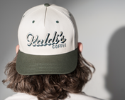 A backwards hat with an dark green brim and a 'Kaldi's Coffee' embroidery.