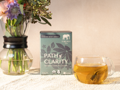 box of path of clarity and a glass mug of yellow tea